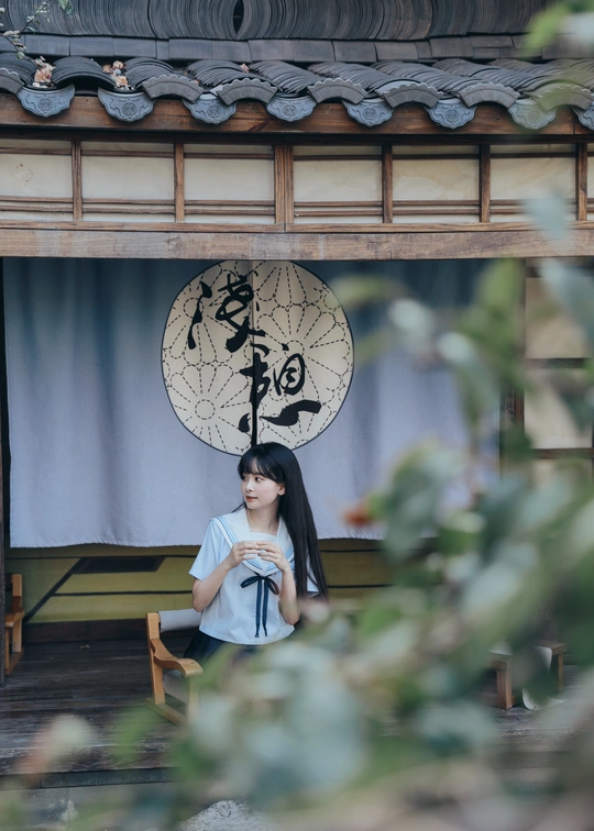 一位年轻女子坐在一栋楼前的蓝色长椅上