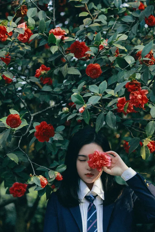 一位穿着西装和领带的女人站在外面 眼睛上戴着红玫瑰。