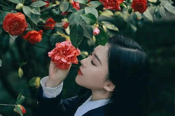 一位年轻女子在花园里闻着红玫瑰