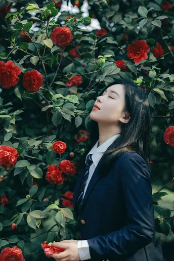 一位穿着西装的年轻女子站在玫瑰花丛中