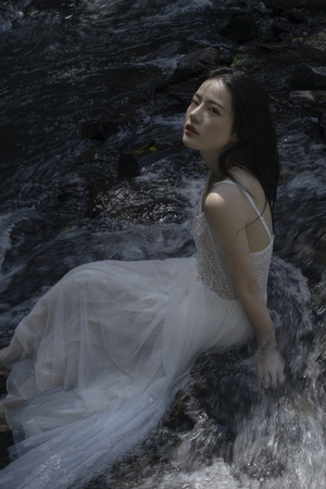 河里或小溪里穿着白色连衣裙的美女