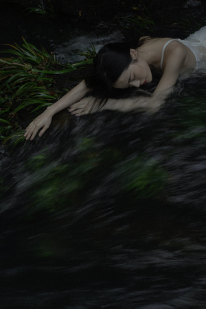 一个穿着白色连衣裙的年轻女子躺在水中 水中漂浮着一具尸体
