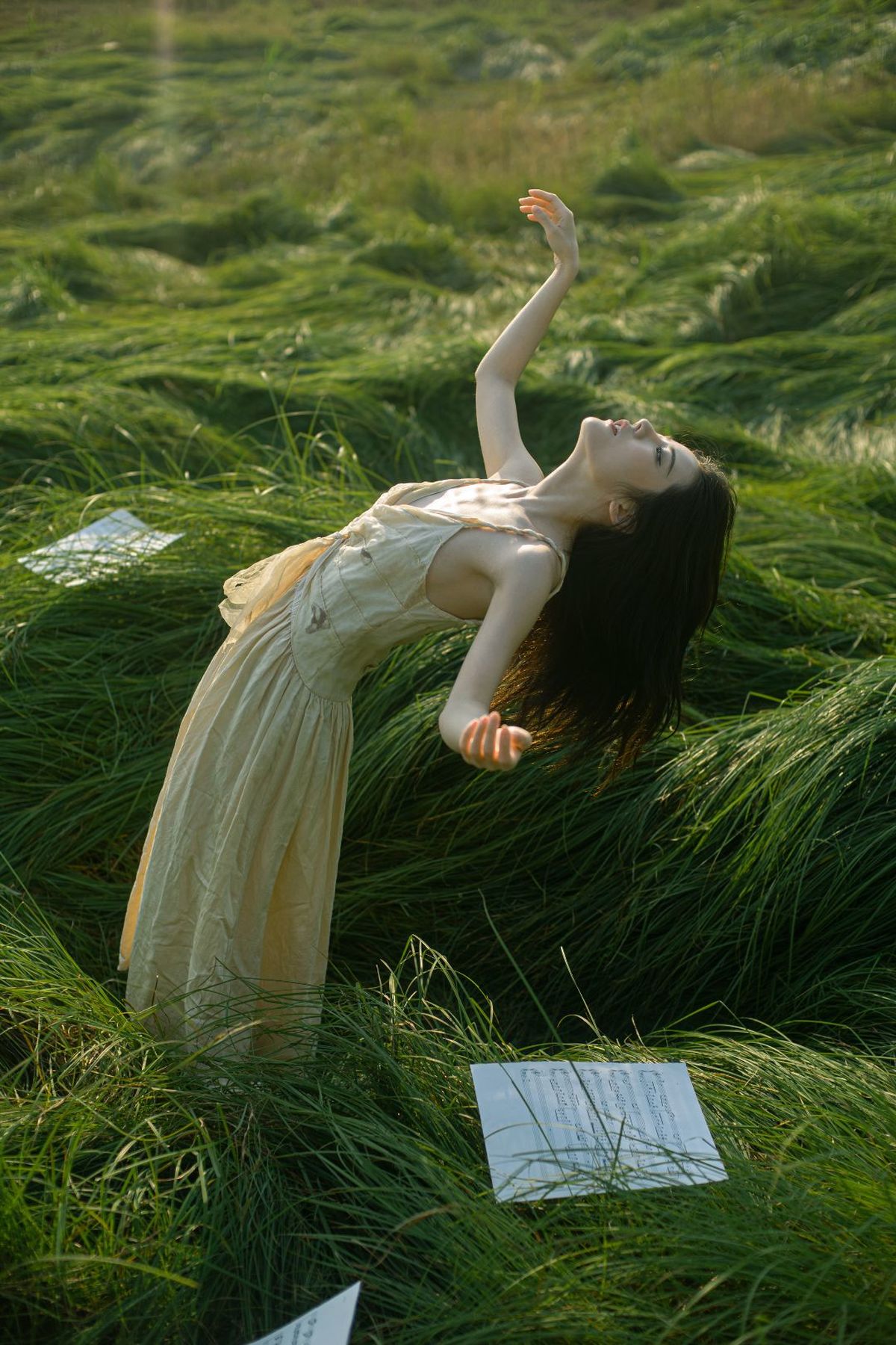 一位穿着连衣裙的女人在一片绿色的草地上漂浮。