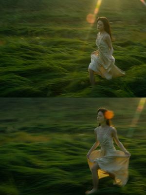 一个穿着白色连衣裙的年轻女子穿过一片绿色的草地。