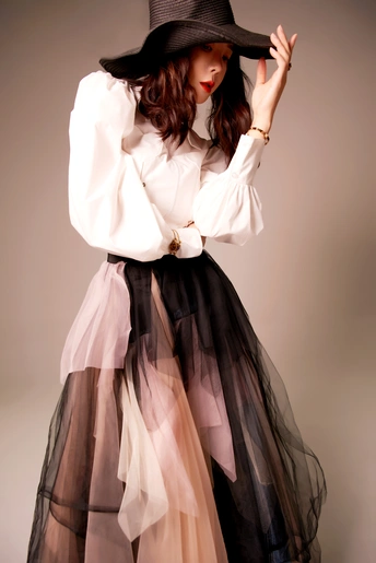 一位穿着白色衬衫和黑色裙子的年轻女子戴着帽子