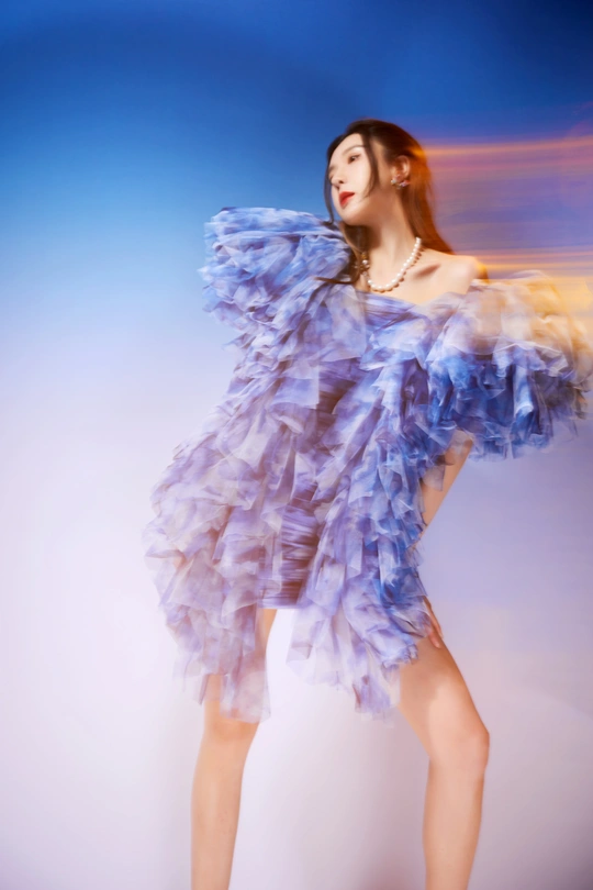 美丽的年轻女子穿着紫裙子在蓝色天空中跳舞