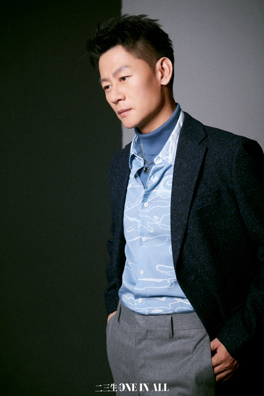 一位穿着蓝色衬衫和领带的年轻人站在一面墙前