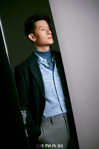 一位穿着蓝色衬衫和领带的年轻人站在一张大型海报前。