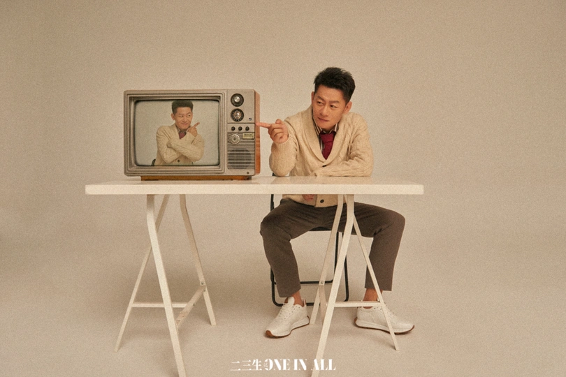 一个人坐在一个小桌子上 桌子上有一张电视的图片。