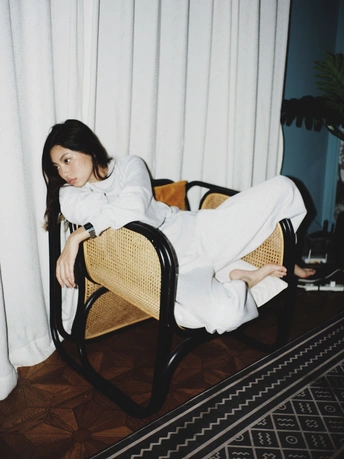 一个穿着白色长袍的年轻女子坐在椅子上