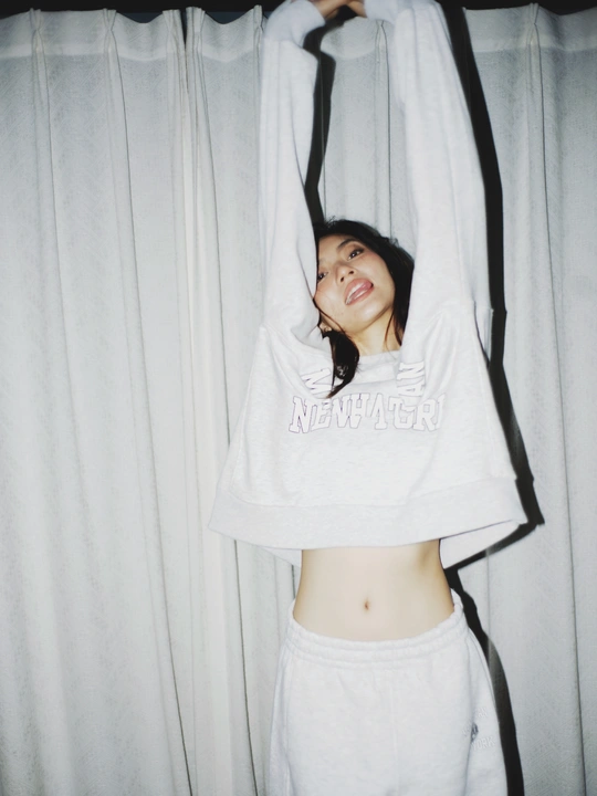 一个年轻女子在床上伸展 一件白色衬衫搭在她的头上