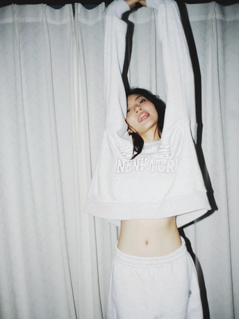 一个年轻女子在床上伸展 一件白色衬衫搭在她的头上