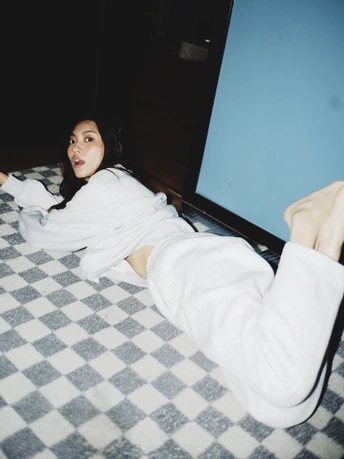 一个穿着白色长袍的年轻女子躺在床上