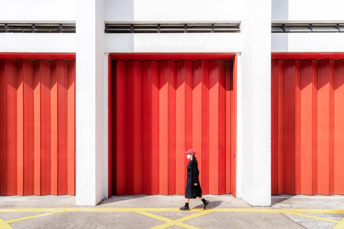 一位穿黑色衣服的女人站在一栋红墙和红门楼前