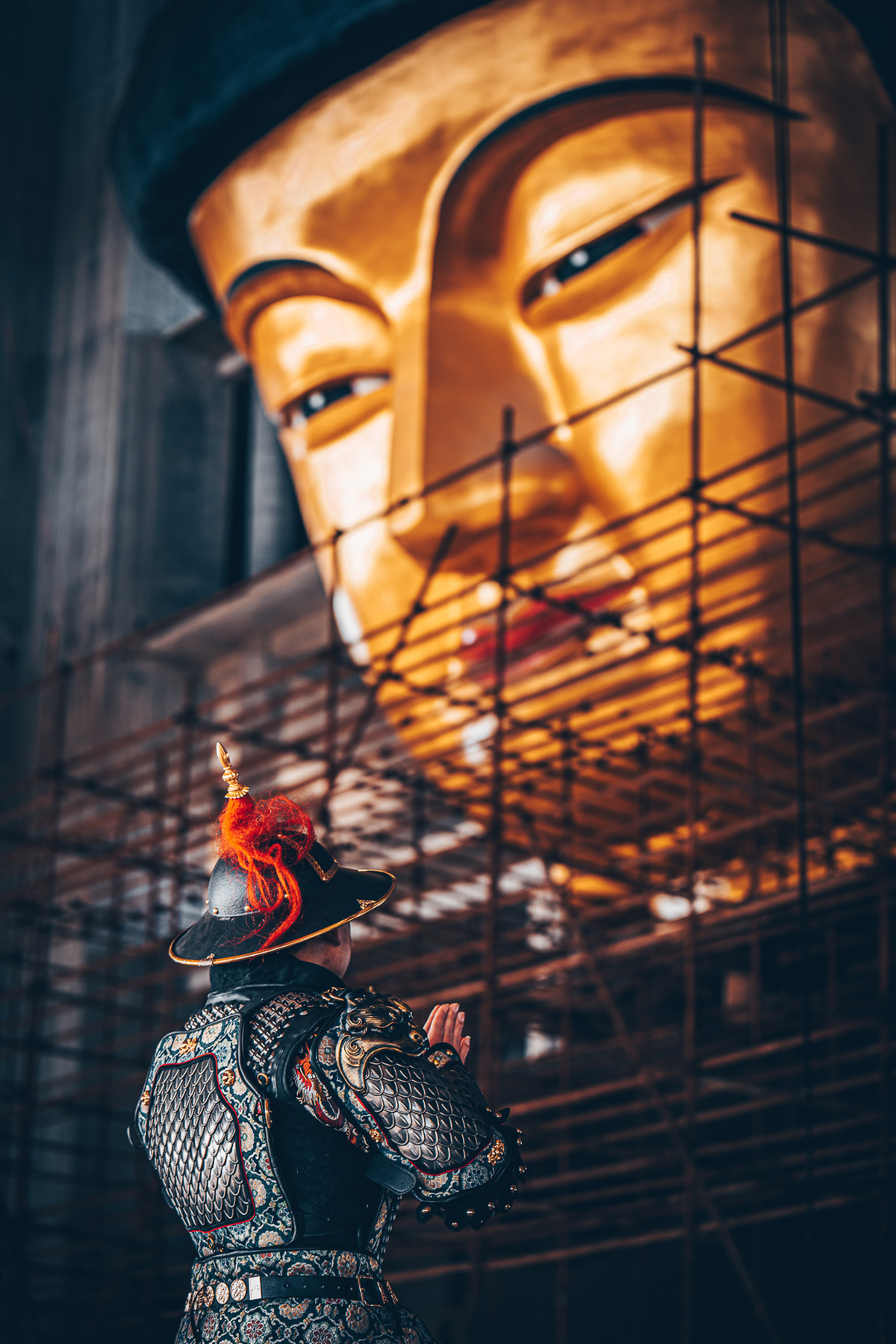 一个人站在脚手架前 手里拿着一个金面具的雕像。
