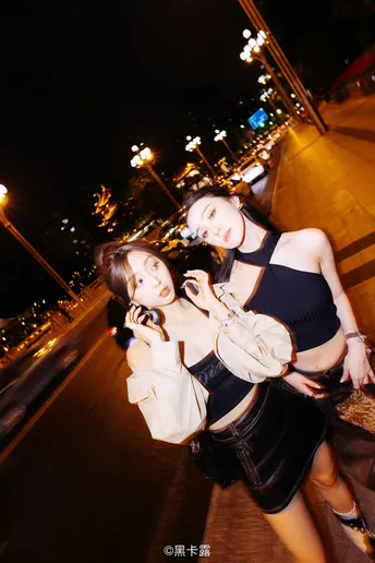 两个年轻女子在夜晚街道人行道上拍照