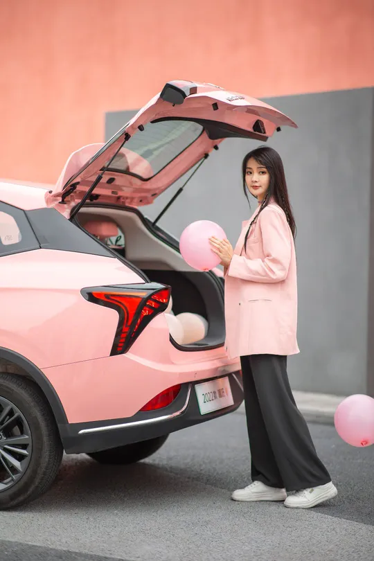 站在一辆粉色汽车旁边的一个女人