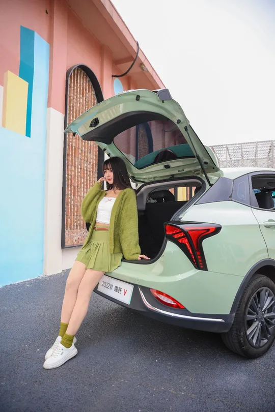 站在一辆打开后备箱的绿色汽车旁的女士