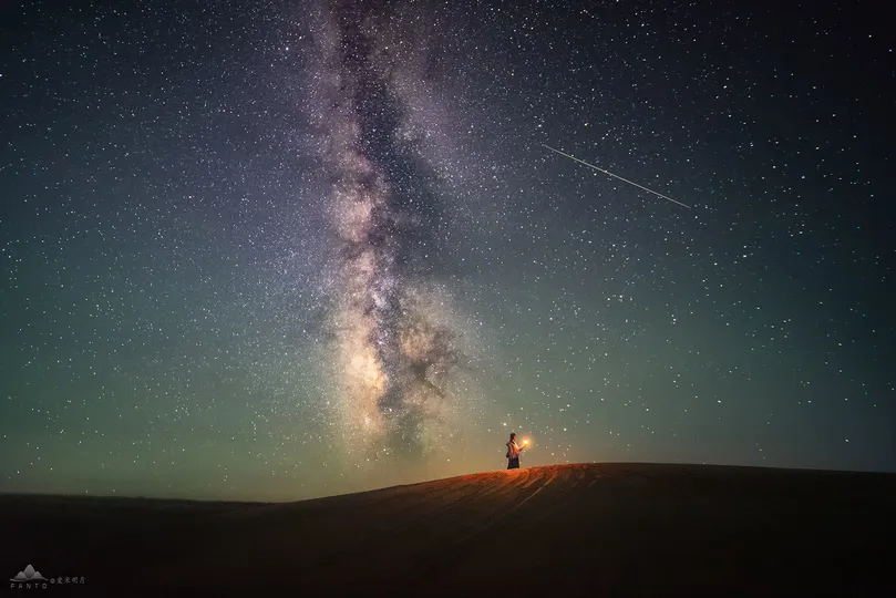 一个人站在山顶上 仰望着夜空中繁星。
