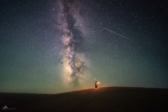 一个人站在山顶上 仰望着夜空中繁星。