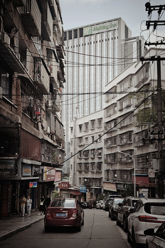 一条街道 街道旁边停满了汽车 还有高大的建筑。