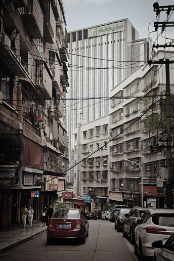 一条街道 街道旁边停满了汽车 还有高大的建筑。