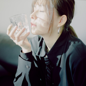 一位年轻女子穿着黑色领带喝着一杯水