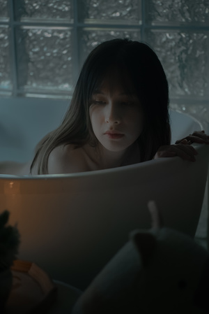 一个年轻女子躺在浴缸里阅读 同时看着窗外。