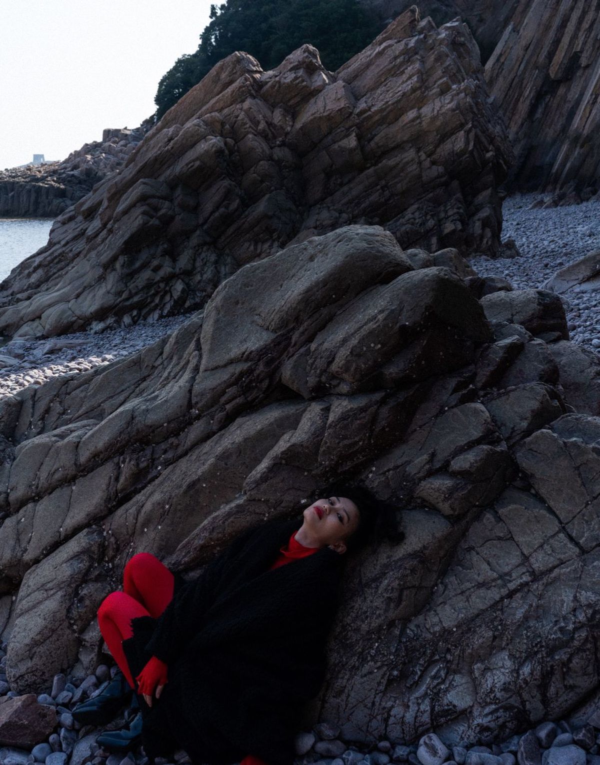 一位女子躺在靠近海洋的岩石海滩上