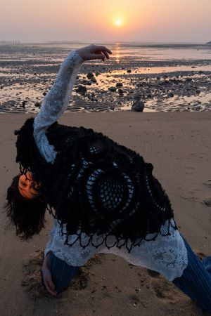 一位年轻女子在日出或日落时在沙滩上练习瑜伽