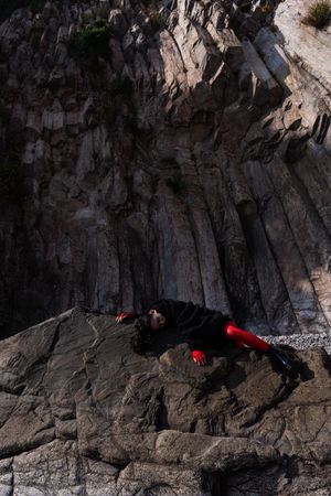 一个人躺在海滩上的岩石悬崖上