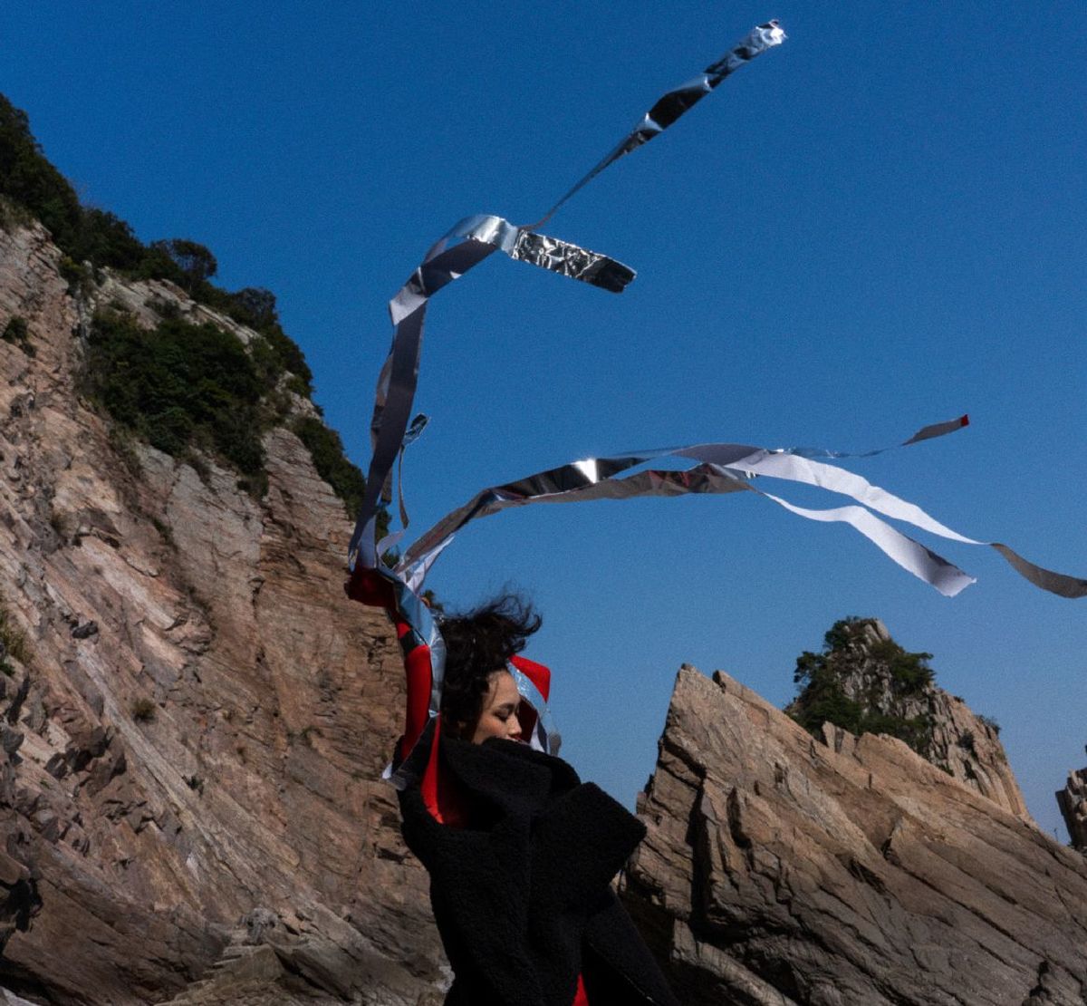 一个男子和一个女子站在一块岩石海滩上 天空中有一只风筝在飞翔。