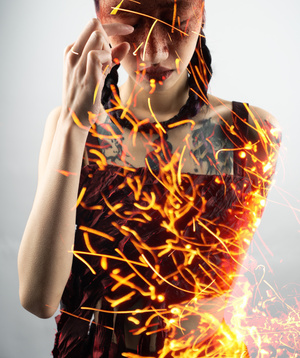 一位年轻女子用双手捂住脸部 火焰覆盖着她的眼睛。