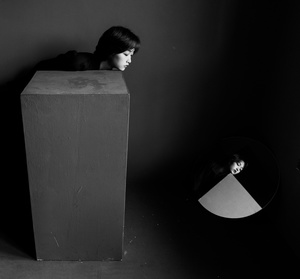 一个年轻女子站在一个黑暗的房间里 她的头在一个箱子里。
