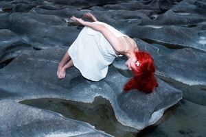 一位红发女子穿着白色裙子在岩石上漂浮