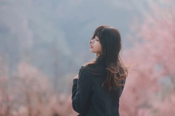 站在粉色树前的年轻女子