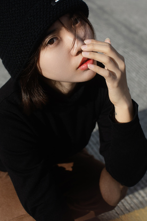 一个戴黑色贝雷帽的年轻女子坐在地板上 用手捂住脸
