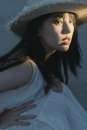 一位年轻女子在海滩上戴着白色帽子享受阳光的肖像