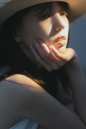 一位美丽的年轻女子戴着大帽子 阳光照耀在她脸上 形成一幅肖像。