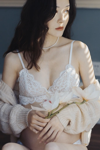 一位穿着白色连衣裙的年轻女子抱着花