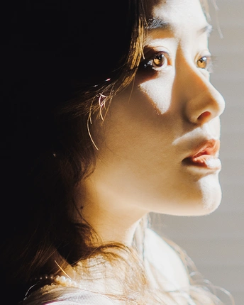 一位年轻女子正在窗口前凝视 阳光照进她的眼睛