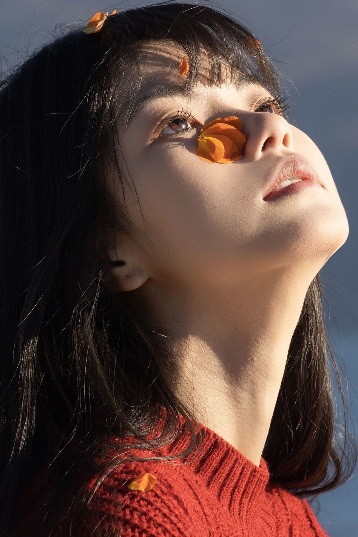 一个戴太阳镜和毛衣的年轻女子抬头望向天空
