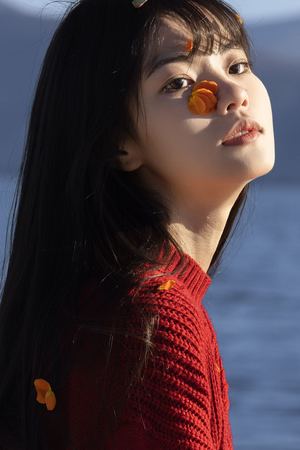 一位穿着红色毛衣 头上有橙色花朵的年轻女子