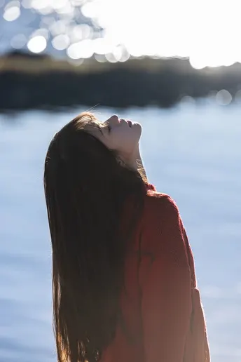 一位穿着红衣服的年轻女子站在海滩上 眺望着海洋或大海。