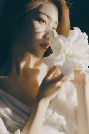 一位穿着白色连衣裙的年轻女子拿着白色花