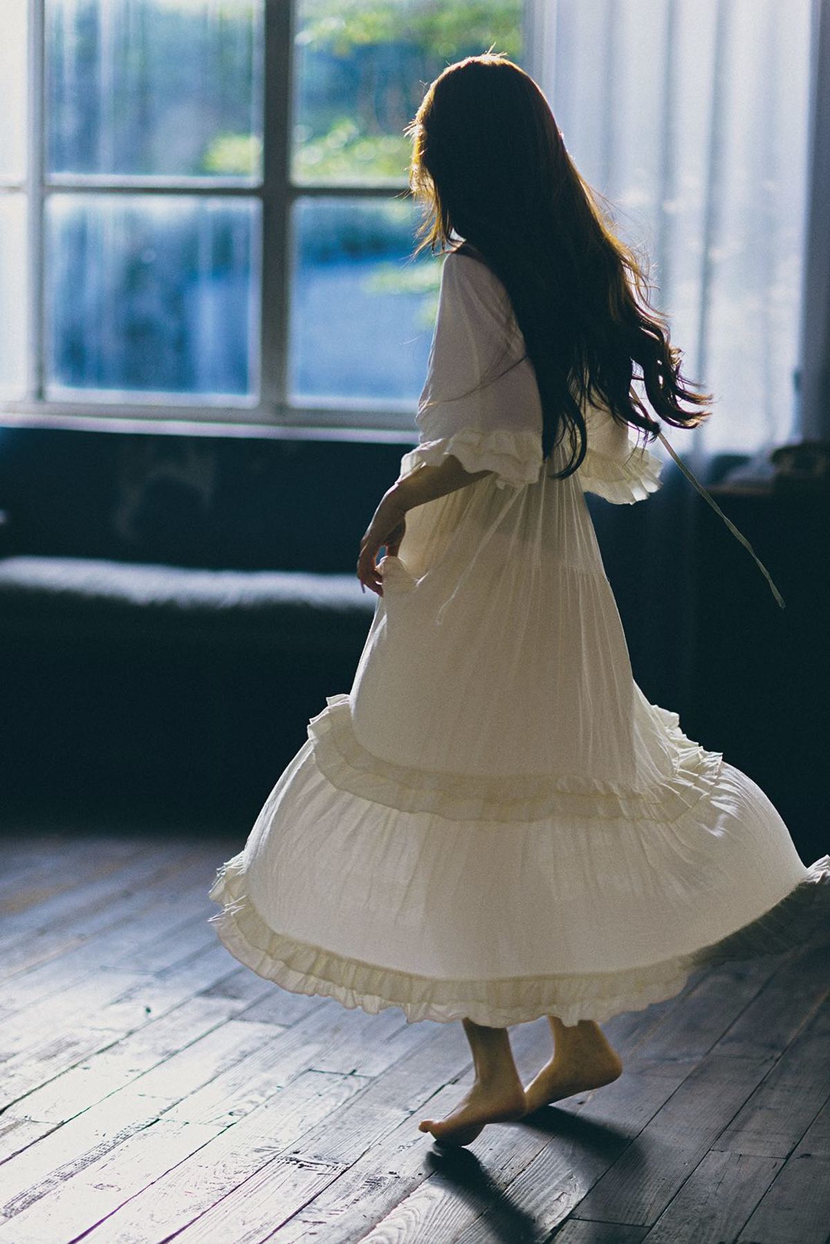 一个穿着白色连衣裙的年轻女子走进了一个光线昏暗的房间。