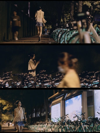 夜晚街道上的一个场景 人们正在走动 一位女士站在一辆自行车旁边。