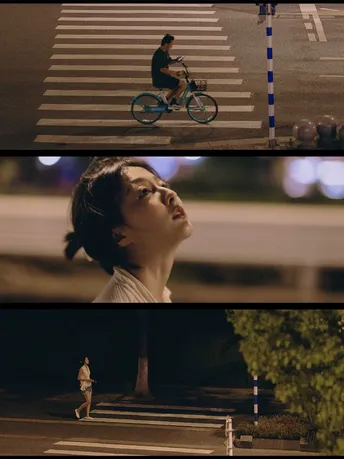 一个电影中的场景 一名女子在夜晚骑自行车穿过街道。