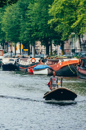 一个人在运河上划着小船 其他人站在水中。