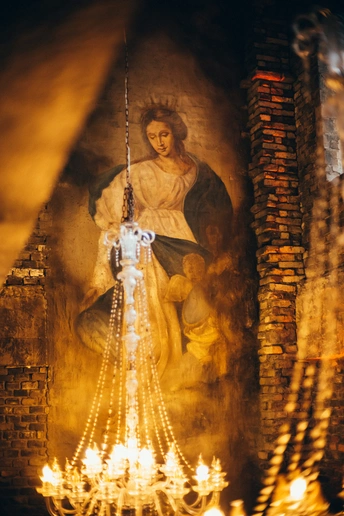 一座教堂里的大型女性雕像被蜡烛和吊灯照亮了。